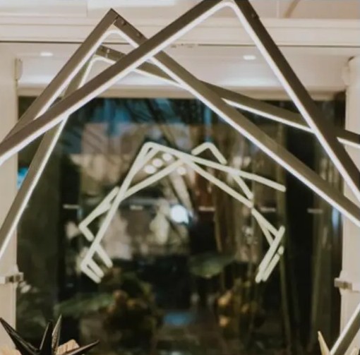 Estructura geométrica iluminada con globos negros y dorados