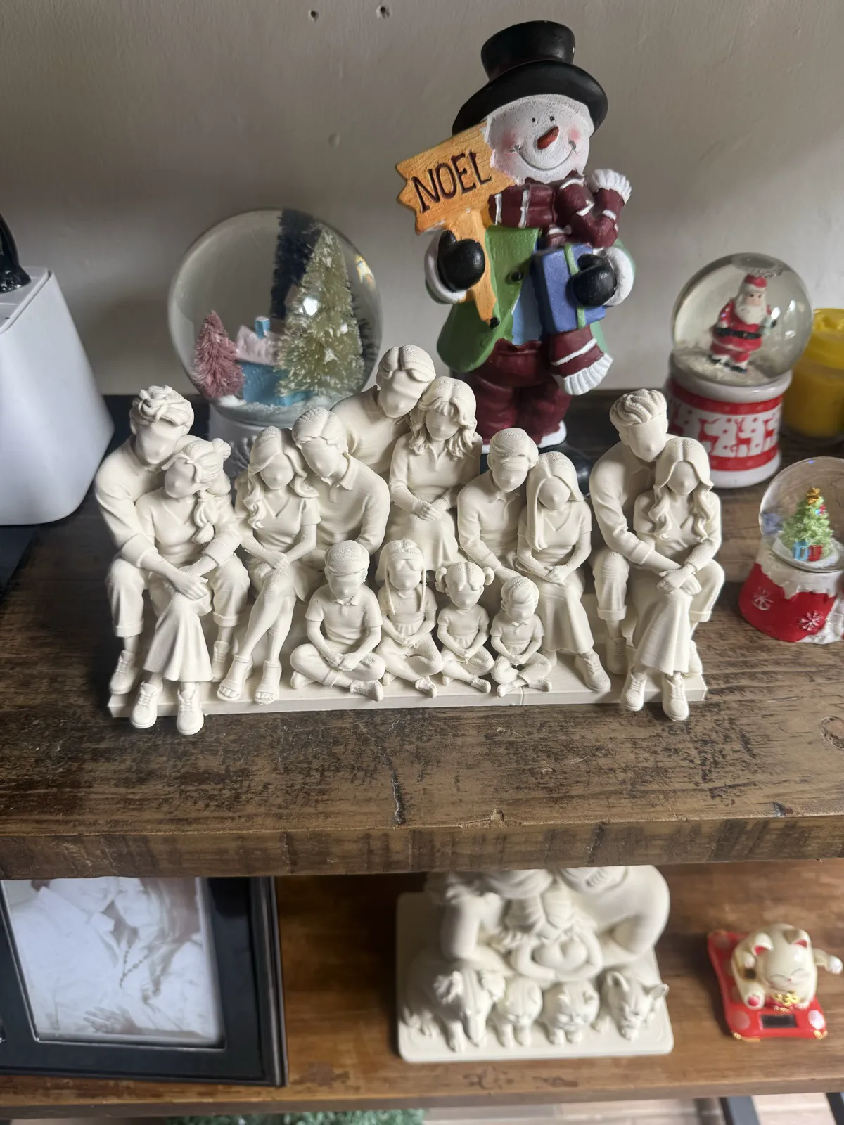 Composición familiar amplia con varias figuras sentadas en una base, sobre un mueble del hogar